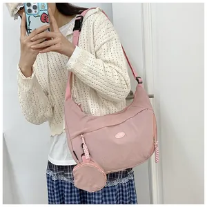 Detailed shot of pink crescent crossbody bag with matching round coin purse and logo
