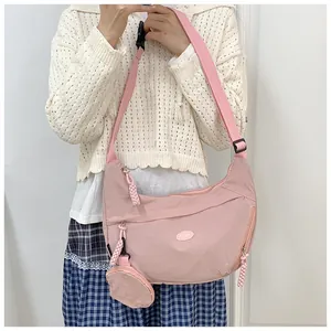 Pink nylon crescent crossbody bag with adjustable strap and small round pouch attachment