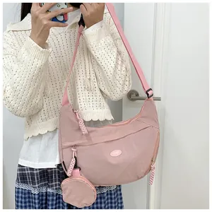 Detailed shot of pink nylon crescent bag featuring a detachable round coin purse on the strap