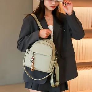 Dettaglio mini zaino in pelle martellata verde chiaro con ciondolo a mucca indossato