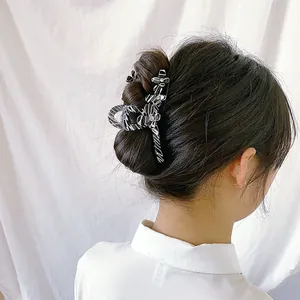 Chic zebra print acetate hair claw with floral accents shown on a model's long dark hair