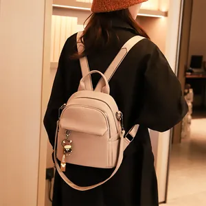 Dettaglio di un mini zaino in pelle beige con ciondolo a forma di mucca sulla schiena
