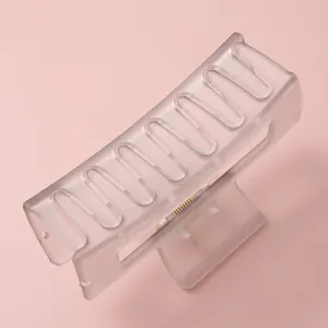 Pince à cheveux rectangulaire translucide givrée avec design ondulé sur fond rose