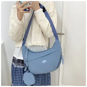 Close-up of blue nylon crossbody dumpling bag with matching coin purse and wide strap