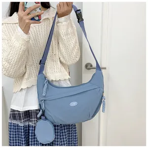 Detail of light blue nylon crescent crossbody bag with adjustable strap and mini coin purse