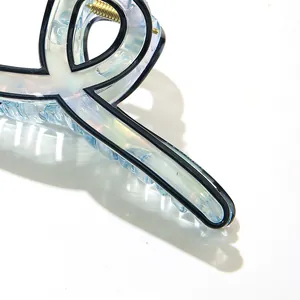 Detailed close-up of blue iridescent acetate hair claw clip with black trim and gold spring