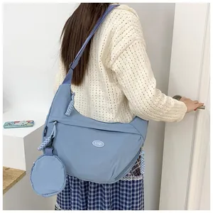 Detail view of the blue crescent shoulder bag with matching round coin purse and logo