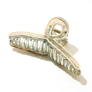 Detail of transparent acetate claw clip with cream edges and golden metal spring