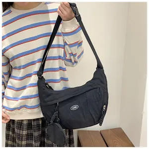 Side view of a black crescent nylon crossbody bag featuring a wide strap and mini coin purse