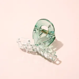 Detailed macro view of the clear teal acrylic mini hair claw clip with golden metal spring