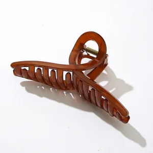 Detailansicht der goldfarbenen Metallfeder an einer glänzenden bernsteinfarbenen Haarspange