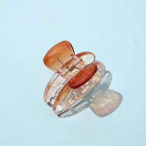 Macro view of a small amber orange hair claw clip with a durable gold metal spring