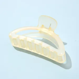 Détail macro d'une grande pince à cheveux mate jaune crème avec des dents solides imbriquées