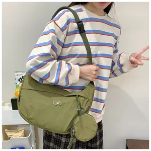 Detail of dark green crescent bag with round pouch and adjustable strap shown on model