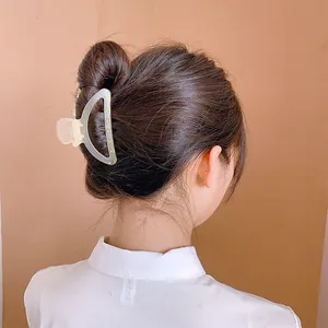 Détail d'une grande pince à cheveux crème mate tenant un chignon sur un mannequin