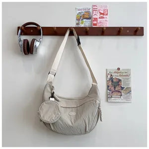 Detail of beige crescent nylon bag with pleated texture and round coin purse accessory