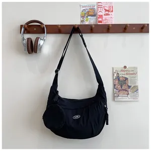 Detail of black crescent crossbody bag featuring an adjustable strap and round coin purse