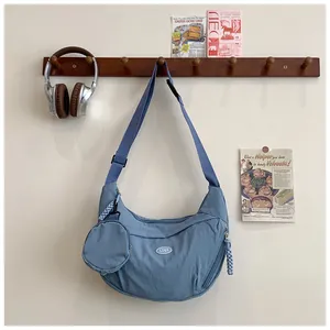 Blue nylon hobo bag with adjustable strap and small coin purse on a wooden wall hook