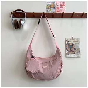 Detail of pink nylon dumpling bag with round coin purse and adjustable strap in home setting