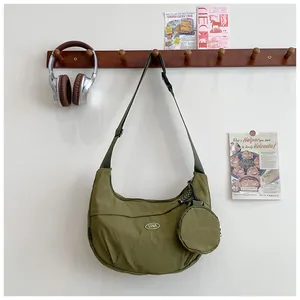 Detail of army green nylon crescent bag with mini round pouch and adjustable strap