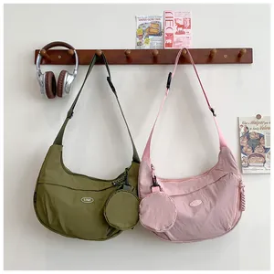 Detail of the nylon crescent bag set showing the adjustable strap and small round coin pouch