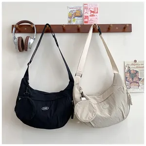 Detail of minimalist moon-shaped crossbody bags in black and beige with round coin pouches