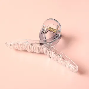 Pinza para el pelo minimalista transparente de 11cm con muelle dorado sobre fondo rosa