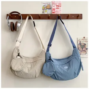 Detail of solid color nylon crescent bags in beige and blue with small coin pouches