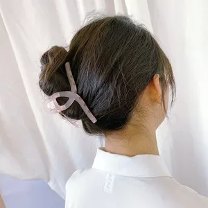 Détail de la pince à cheveux rose mat à pois rouges sur les cheveux bruns du modèle