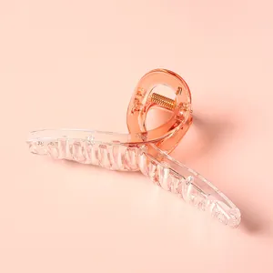 Detalle de una pinza para el pelo grande rosa melocotón translúcido con muelle dorado
