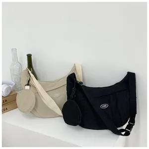 Detail of crescent nylon bags in beige and black with round coin pouches on straps