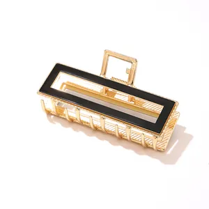 Macro shot of large golden rectangular metal hair claw clip with black enamel detail