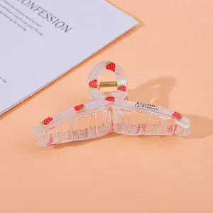 Detail of transparent strawberry print hair claw clip with golden metal spring