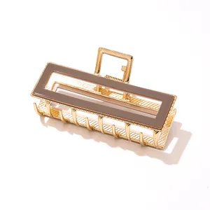 Detail of a rectangular gold metal hair claw clip with a glossy brown acetate inlay finish