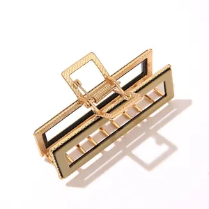 Golden rectangular metal hair claw clip with beige acetate finish on white background