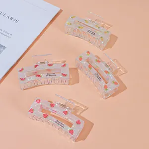 Detail of colorful acrylic fruit hair claws featuring strawberry and pineapple patterns
