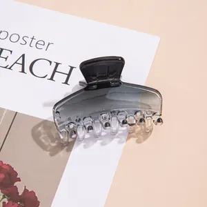 Close-up of translucent grey gradient hair claw clip on soft beige background