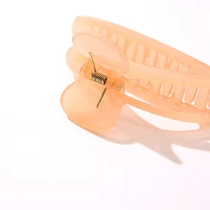 Primer plano de pinza para el pelo de resina color melocotón con muelle metálico fuerte