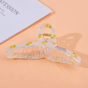 Detail view of transparent acrylic hair claw with pineapple print and golden spring