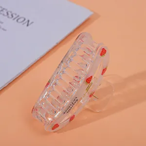 Close-up of a clear acrylic strawberry hair claw clip with a metal spring mechanism