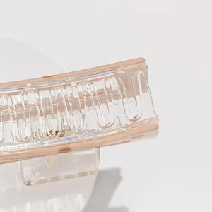 Detailed close-up of a transparent acrylic claw clip with cream edges and metal spring