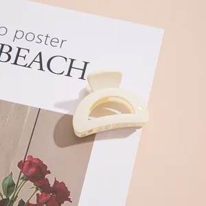 Gros plan d'une pince à cheveux en acrylique blanc crème sur un fond rose esthétique