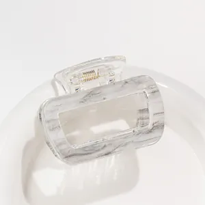 Detail of a medium rectangular acrylic hair claw with grey marble pattern on a white tray