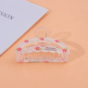 Detail of transparent acrylic hair claw with red floral pattern and Barrette La France text