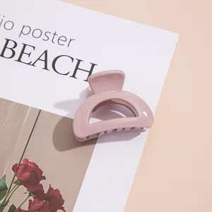 Gros plan d'une petite pince à cheveux en acrylique rose lotus brillant sur fond décoré