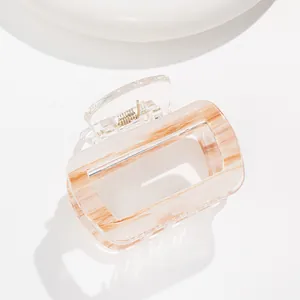 Detail of a square striped hair claw clip showing amber marble texture and gold metal spring