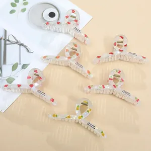Detailed macro view of large acrylic hair claws with colorful fruit and floral prints