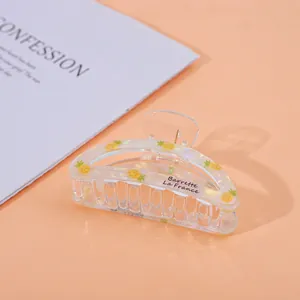 Detailed view of a transparent hair claw clip featuring yellow pineapple patterns