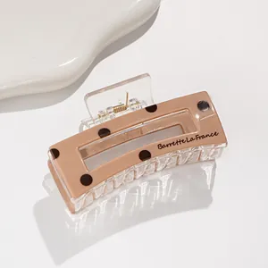 Detail of a rectangular polka dot hair claw clip with a khaki finish and metal spring