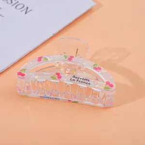 Detailed view of clear acrylic hair claw clip with pink cherry print and French text